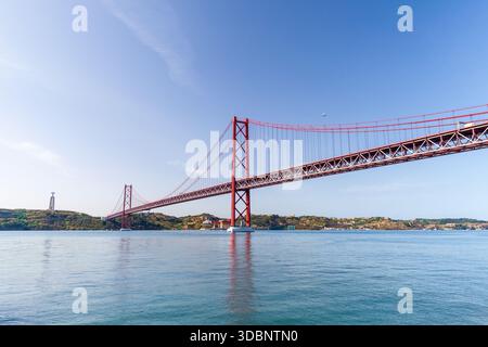 25 de Abril Bridge, eine rote Hängebrücke ähnlich dem Golden Gate in San Francisco. Eine markante rote Hängebrücke überspannt das ruhige Wasser und verbindet Lisbo Stockfoto