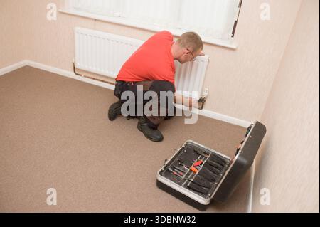 Ein Installations- und Heizungsingenieur arbeitet an der Wartung eines Gaskessels und eines Heizkörpers. Stockfoto