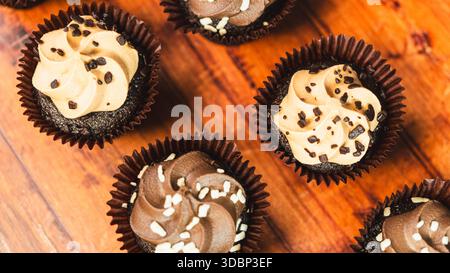Gemischte Mini-Cupcakes aus Schokolade und Karamell, wunderschön auf einem Holzbrett angeordnet. Feuchte, mundgerechte Desserts, perfekt für Partys und süße Genüsse Stockfoto