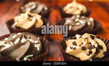 Gemischte Mini-Cupcakes aus Schokolade und Karamell, wunderschön auf einem Holzbrett angeordnet. Feuchte, mundgerechte Desserts, perfekt für Partys und süße Genüsse Stockfoto