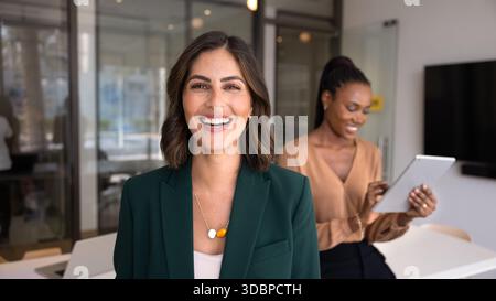Glückliche, schöne hispanische Geschäftsfrau posiert für Kopfschuss im Büro Stockfoto