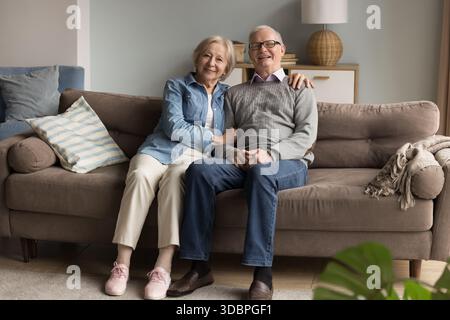 Porträt glückliches lächelndes älteres Paar, das eng zusammen auf der Couch sitzt Stockfoto