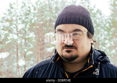 Großer Heckmann mit Schnurrbart und ordentlichem Bart aus nächster Nähe vor verschneiten Winterwald Hintergrund. Stockfoto