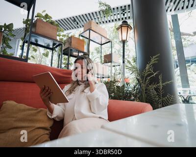 Frau telefoniert mit einem Tablet in einem Café. Stockfoto