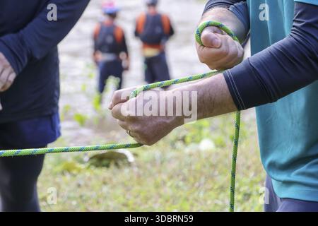 Aktive Hände für Erwachsene halten das grüne Seil fest und bereiten sich auf Abenteuer im Freien vor. Sie zeigen Entschlossenheit, Teamwork-Spirit bei Tageslicht Stockfoto