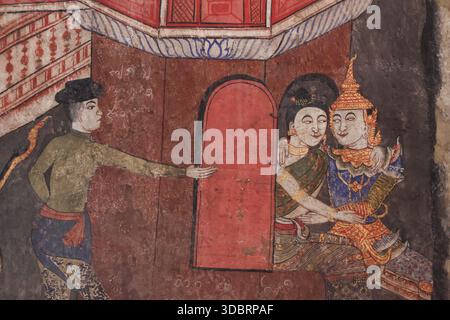 Antike traditionelle thailändische Wandmalerei an der Tempelwand zeigt den Mann, der mit dem Finger auf ein Paar zeigt, das friedlich verliebt im Fenster des roten Turmgebäudes aussieht Stockfoto