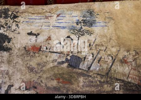 Altes verwittertes Wandgemälde an der Tempelwand, das die historische Szene einer traditionellen Bootsruderprozession mit asiatischen Figuren zeigt, die Ruder halten und wir Stockfoto