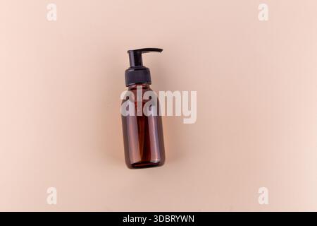 Pumpflasche aus bernsteinfarbenem Glas auf beigefarbenem Hintergrund. Stockfoto