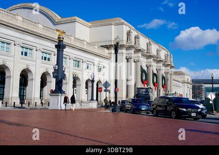 Washington, D.C., USA - 14. Dezember 2025: Große Kränze mit roten Bögen zieren die Vorderseite der Washington Union Station, während die Tourbusse darunter vorbeifahren. Stockfoto