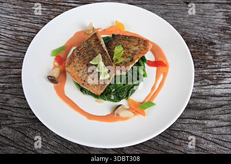 Seebarschsteak serviert mit Salat, gewürzt mit Olivenöl und Zitronenscheiben Stockfoto