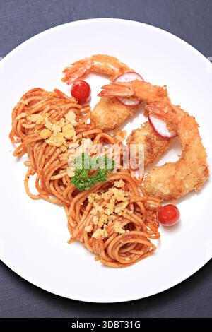 Spaghetti mit Tomatensauce und gebratenen Garnelen, serviert auf einem weißen Teller, thailändische und italienische Fusion-Gerichte Stockfoto