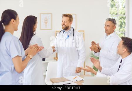 Eine Gruppe von Ärzten gratuliert einem Kollegen mit Applaus, Nahaufnahme Stockfoto
