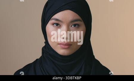 Portrait ernsthafte asiatische muslimische Frau mit schwarzem Hijab, die in die Kamera blickt einsam traurige weibliche islamische Kopftuch Identität Diskriminierung Koreanisch Stockfoto