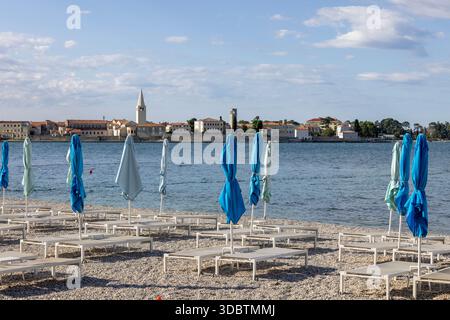 Porec, Kroatien, Istrien - 30. September 2023: Blick vom Strand mit Sonnenschirmen und Liegestühlen auf die Stadt mit dem Glockenturm der Basilika von EU Stockfoto