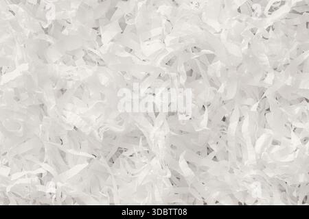 Weiße, geschredderte Papierstruktur mit gewellten Streifen, die eine helle, festliche Oberfläche für Verpackungen, Bastelarbeiten und Designhintergründe schaffen. Konzept des Feierns, Öko Stockfoto