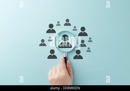 Konzept für Talentsuche und Personalbeschaffung. Halten Sie die Hand über die Symbole des Kandidaten mit einer Lupe, um die Gewinnung von Talenten, die Rekrutierung und die Mitarbeiter zu symbolisieren Stockfoto