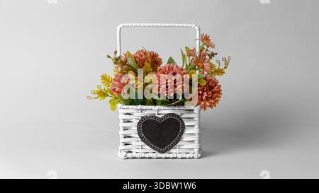 Schöne Plastikblumendekoration im Korb auf grauem Hintergrund Stockfoto