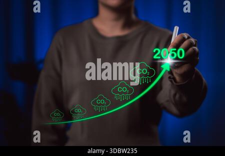Prognostizierte CO2-Reduktionsziele für die Klimaziele bis 2050. Eine Person zeichnet einen aufsteigenden grünen Pfeil mit CO2-Symbolen und das Jahr 2050, Kohlendioxid Stockfoto