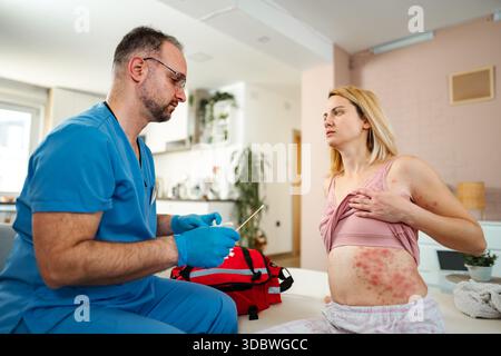 Arzt untersucht weibliche Patientin mit Hautausschlag während Hausbesuch Stockfoto