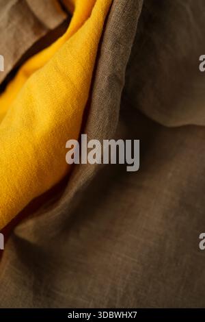 Zufällig platziertes braunes und heißes gelbes Leinenstoff. Dunkelbraune und goldene Senfgelbe Farbe. Modell Aus Stoff-Leinen. Geringe Schärfentiefe. Kopierbereich Stockfoto