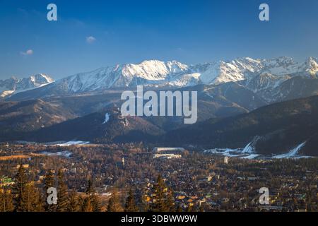 Malerischer Blick auf eine Stadt am Fuße der Berge, bedeckt mit Schnee unter einem hellblauen Himmel. Zakopane Stadt am Fuße des Tatra Moun Stockfoto