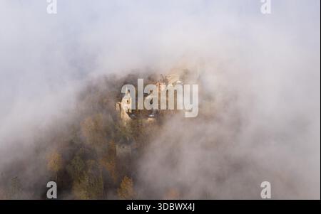 Aus der Vogelperspektive blickt die Burg Frankenstein durch ein Meer aus ätherischem Nebel, eine mittelalterliche Silhouette vor dem gedämpften, trüben Himmel, Mühltal, Hessen, Deutschland. Stockfoto