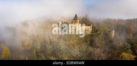 Weitwinkelpanorama aus der Vogelperspektive, die Burg Frankenstein durchdringt den ätherischen Nebel, ihre antiken Steine bilden einen starken Kontrast zu der weichen Umgebung Stockfoto