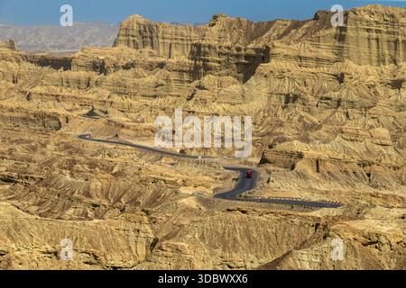 Blick auf gewundene Straßen schlängelt sich durch eine weite, trockene Landschaft aus felsigen Bergen unter klarem Himmel, Makran Coastal Highway, Belutschistan, Pakistan. Stockfoto