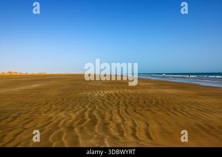 Blick auf den goldenen Sand und das türkisfarbene Meer unter einem klaren blauen Himmel, die rhythmischen Wellen küssen sanft die Küste in Kund Malir, Balochistan, Pakistan. Stockfoto