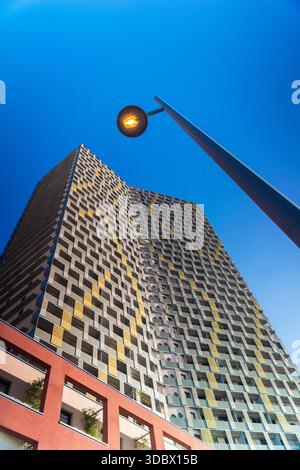 Blick auf ein modernes Gebäude mit einem einzigartigen Fassadenmuster erhebt sich zum intensiven blauen Himmel, gegenüber einer Straßenlaterne, Wien, Österreich. Stockfoto