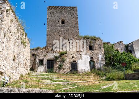 Craco, Italien-25. april 2025: Normannischer Turm zwischen den Ruinen der Geisterstadt Craco an einem Sommertag Stockfoto