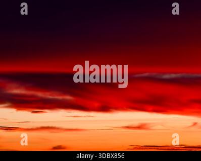 Sonnenuntergangshimmel mit dramatischen roten Wolken und dunklem Horizont abstrakter orangefarbener Verlauf weiche Bewegungsunschärfe warme atmosphärische Töne Digital Art Natur Hintergrund Stockfoto