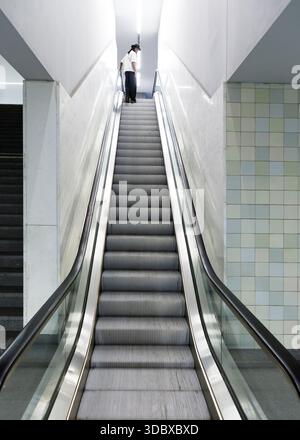 Eine Person fährt mit einer Rolltreppe nach oben. Stockfoto