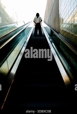 Eine Person steht auf einer Rolltreppe und schaut nach oben. Stockfoto