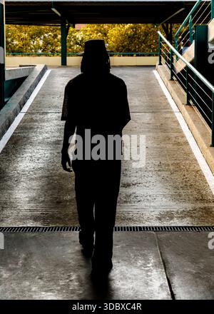 Eine Person mit Hut geht eine Rampe in einem Parkhaus hinunter. Stockfoto