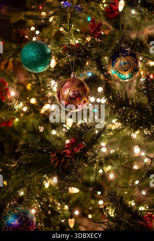 Wunderschöne und farbenfrohe Weihnachtsdekoration auf einer Kiefer, Nahaufnahme von Baumkugeln und Lichter auf dem Weihnachtsbaum. England, Großbritannien Stockfoto