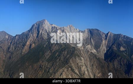 Aus der Vogelperspektive sehen Sie zerklüftete, felsige Gipfel, die den klaren blauen Himmel durchstechen, ihre schroffen Gesichter mit Schatten und Licht, Gilgit, Gilgit Baltistan, Pakistan. Stockfoto