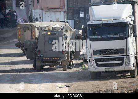 Nablus, Palästina. Dezember 2025. Ein israelischer Soldat richtet seine Waffe auf Palästinenser während eines Überfalls auf das Flüchtlingslager Askar östlich von Nablus im Westjordanland. Israelische Truppen plünderten palästinensische Häuser und Geschäfte im Lager auf der Suche nach palästinensischen Militanten. Ein Palästinenser wurde bei der Suche verletzt. Quelle: SOPA Images Limited/Alamy Live News Stockfoto