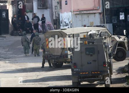 Nablus, Palästina. Dezember 2025. Israelische Soldaten bewachen Militärfahrzeuge und nehmen Positionen bei einem Angriff auf das Flüchtlingslager Askar östlich von Nablus in der Westbank ein. Israelische Truppen plünderten palästinensische Häuser und Geschäfte im Lager auf der Suche nach palästinensischen Militanten. Ein Palästinenser wurde bei der Suche verletzt. Quelle: SOPA Images Limited/Alamy Live News Stockfoto