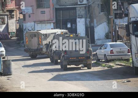 Nablus, Palästina. Dezember 2025. Israelische Militärfahrzeuge blockieren die Straße während eines Überfalls auf das Flüchtlingslager Askar östlich von Nablus im Westjordanland. Israelische Truppen plünderten palästinensische Häuser und Geschäfte im Lager auf der Suche nach palästinensischen Militanten. Ein Palästinenser wurde bei der Suche verletzt. Quelle: SOPA Images Limited/Alamy Live News Stockfoto
