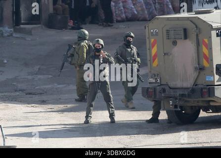 Nablus, Palästina. Dezember 2025. Israelische Soldaten bewachen Militärfahrzeuge und nehmen Positionen bei einem Angriff auf das Flüchtlingslager Askar östlich von Nablus in der Westbank ein. Israelische Truppen plünderten palästinensische Häuser und Geschäfte im Lager auf der Suche nach palästinensischen Militanten. Ein Palästinenser wurde bei der Suche verletzt. Quelle: SOPA Images Limited/Alamy Live News Stockfoto
