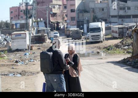 Nablus, Palästina. Dezember 2025. Palästinenser stehen auf der Straße, während israelische Militärfahrzeuge im Hintergrund bei einem Angriff auf das Flüchtlingslager Askar östlich von Nablus im Westjordanland sichtbar sind. Israelische Truppen plünderten palästinensische Häuser und Geschäfte im Lager auf der Suche nach palästinensischen Militanten. Ein Palästinenser wurde bei der Suche verletzt. Quelle: SOPA Images Limited/Alamy Live News Stockfoto