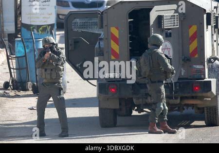 Nablus, Palästina. Dezember 2025. Ein israelischer Soldat richtet seine Waffe auf Palästinenser während eines Überfalls auf das Flüchtlingslager Askar östlich von Nablus im Westjordanland. Israelische Truppen plünderten palästinensische Häuser und Geschäfte im Lager auf der Suche nach palästinensischen Militanten. Ein Palästinenser wurde bei der Suche verletzt. Quelle: SOPA Images Limited/Alamy Live News Stockfoto
