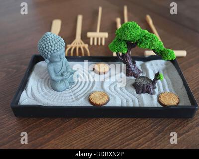 Buddha-Statue im Zen-Stil. Miniatur-Meditations- und Entspannungsset für Zuhause auf dem Tisch. Östlicher Steingarten. Stockfoto