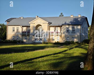 Elegantes Herrenhaus aus dem frühen 20. Jahrhundert in Lipinki, Polen, 1909 erbaut mit neoklassizistischer Fassade, Giebel und blumengeschmücktem Balkon. Stockfoto