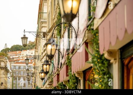 Lissabon Portugal 5. Dezember 2025 Eine Reihe von Straßenlaternen und festlichem Grün schmückt historische Gebäudefassaden Stockfoto