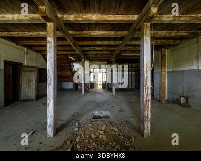 Sonnendurchflutete Tür in leerer Industriehalle mit Holzbalken und Treppe Stockfoto