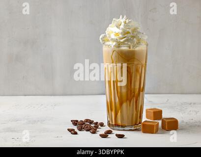 Glas Karamell Latte Kaffee dekoriert mit Schlagsahne auf weißem Tisch Stockfoto