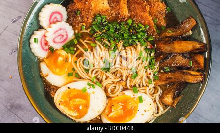 Knuspriges Hühnchen-katsu-Ramen mit weichgekochtem Ei, Bambussprossen und naruto-Fischkuchen. Reichhaltige, herzhafte Brühe. Perfektes japanisches Komfortessen in einer Schüssel. Stockfoto