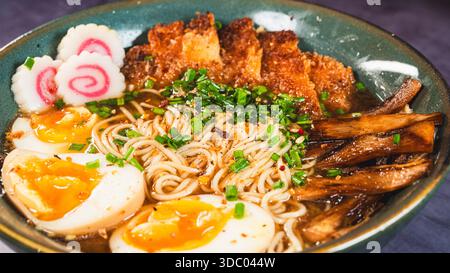 Knuspriges Hühnchen-katsu-Ramen mit weichgekochtem Ei, Bambussprossen und naruto-Fischkuchen. Reichhaltige, herzhafte Brühe. Perfektes japanisches Komfortessen in einer Schüssel. Stockfoto
